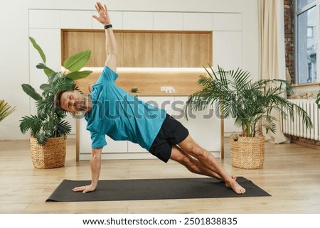 Man performing a side plank exercise on a yoga mat indoors, surrounded by plants, focusing on core strength and balance.