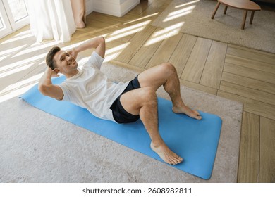 Man Performs an Energizing Workout at Home, Focusing on Core Strength Through Crunches on a Mat