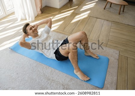Man Performs an Energizing Workout at Home, Focusing on Core Strength Through Crunches on a Mat