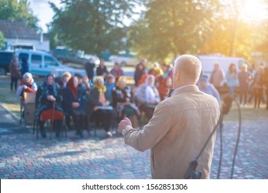 A man performs in front of an audience in the open air