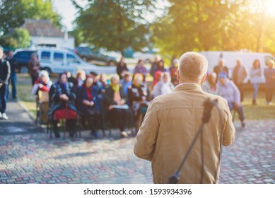 A man performs in front of an audience in the open air