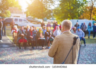 A man performs in front of an audience in the open air