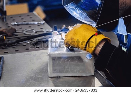 Man performs welding work at his workplace. Welding an aluminum tank with an argon welding machine.