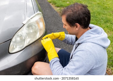 Man Person Worker Putting Gloves On For Cleaning Car Dirty Foggy Headlights Taped To Protect Paint On Home Driveway Of House Outside