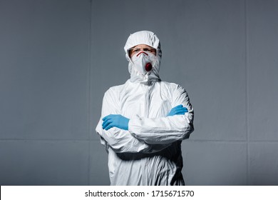 Man In Personal Protective Equipment Standing With Crossed Arms On Grey