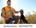 Man, pet dog and outdoor for hunting season, stroke and search for prey together in nature. Mature person, rub animal and hunter helper in field to guide in woods, affection and tracking in sports