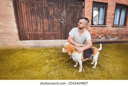 Man petting a beagle in front of a brick house. - Powered by Shutterstock