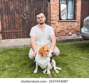 Man petting a beagle in front of a brick house. - Powered by Shutterstock