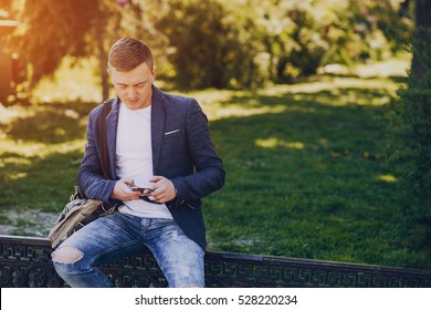 A Man With A Phone And Tablet Computer Running Outdoors On A Sunny Day