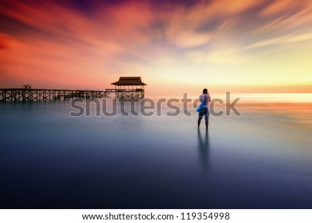 Man photographed sunset near the pier standing in water