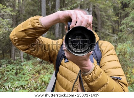 Man photographer taking photo in nature, view on lens