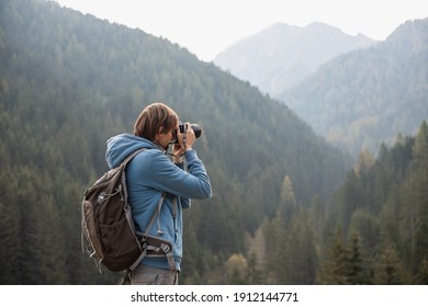 Man photographer taking photographs with digital camera in a mountains. Creative professional photographing. Travel, hobby and active lifestyle concept