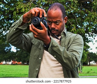 Man photographer taking photos with a mirrorless camera. Black man capturing wonder of outdoors. Nature hobby, travel, lifestyle, people concept          - Powered by Shutterstock