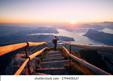 Man photographing landscape with lake and mountains at beautiful sunrise. View from Mount Pilatus, Lucerne, Switzerland - Powered by Shutterstock