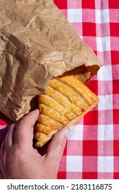 Man Picking An Apple Turnover In A Brown Paper Bag Outdoors On A Gingham Cloth. Environmentally Friendly Recycle Packaging