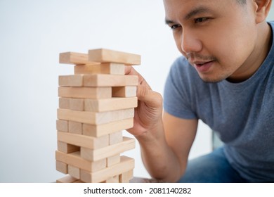 Man Picking Up Blocks While Playing Tower Of Blocks