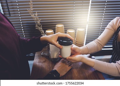 Man Picking Up Coffee From A Barista At The Counter In A Coffee Shop.