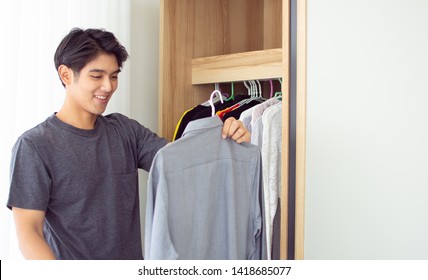 A Man Is Picking Up His Shirt From The Wardrobe In His Dressing Room