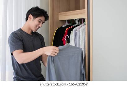 A Man Is Picking Up His Shirt From The Wardrobe In His Dressing Room