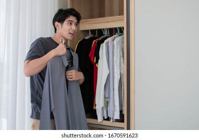 A Man Is Picking Up His Shirt From The Wardrobe In His Dressing Room