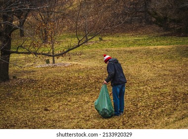 Man Picking Up Trash And Putting It Inside Large Bag In Midwestern Park Early In Spring