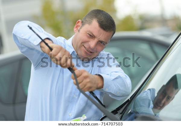 man picking up windscreen\
wiper