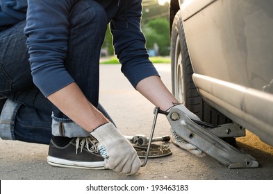 Man Picks Up A Car Jack To Change A Tire