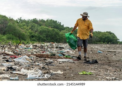 Man picks up plastic garbage on beach in the morning, Panama, Central America.