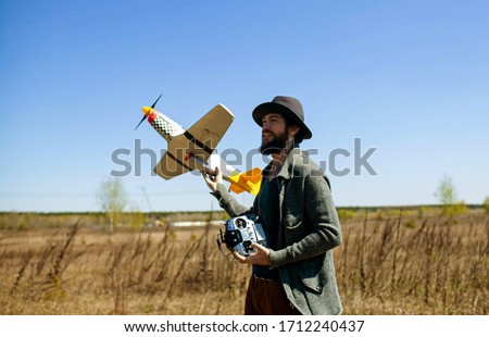 Man Piloting Tiny Radio Controlled Helicopter With Radio Remote Control outdoor.