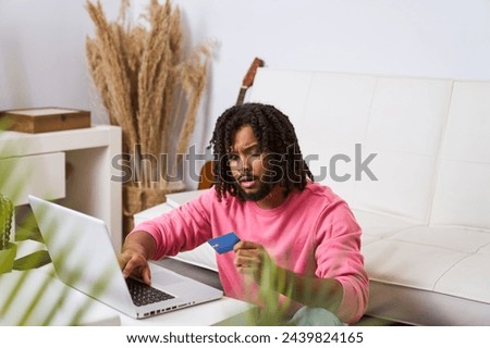 A man in a pink shirt is using a laptop to pay for something. Concept of convenience and modernity, as the man is able to complete a transaction from the comfort of his own home