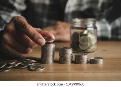 

The Man Placed The Coin On The Pile Of Coins On The Table.