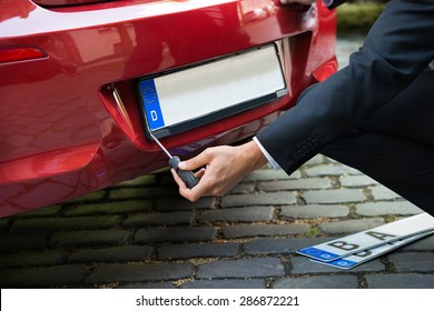 Man Placing New Empty White Number Plate On His Red Car