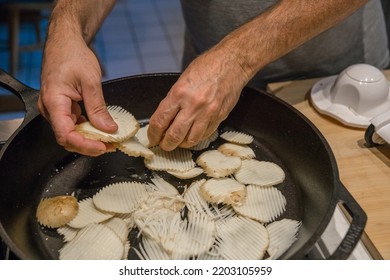 Man Placing Ridged Slices Of Raw Potato Into Frying Pan After Slicing Them With A Mandolin In Home Kitchen.