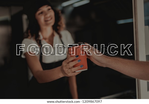 Man In A Plaid Shirt Buys Coffee In A Food Truck.\
Black Beard. Girl With Curly Hair.. Fast Eating Place. Service\
Personal. Opened Window. Professional Work Uniform. Sunny Day.\
Buyer And Seller.