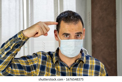 Man In Plaid Shirt And Mask By Covid-19 Virus In The Living Room At Home