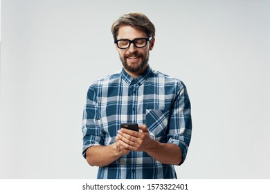 man in a plaid shirt with a mobile phone and glasses