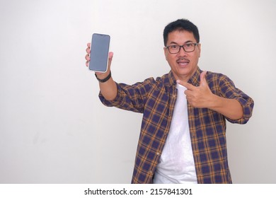 A man in a plaid shirt over a white t-shirt holding a cellphone; explaining something about the cellphone he is holding. - Powered by Shutterstock