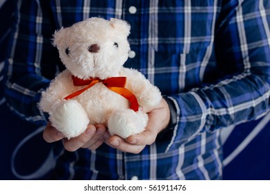 A Man In A Plaid Shirt With A Teddy Bear In Hands