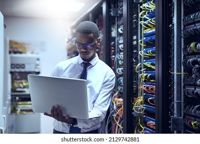 The man with the plan. Cropped shot of a IT technician working on his laptop while standing inside of a server room.
