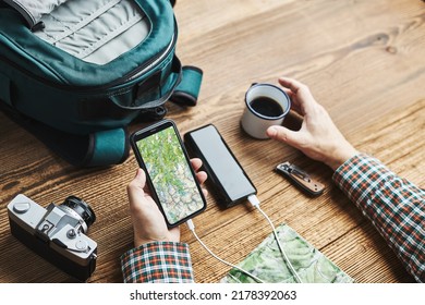 Man Planning Next Vacation Trip While Journey Searching Travel Destination And Routes Using Navigation Map On Mobile Phone. Charging Smartphone With Power Bank. Using Technology While Travelling