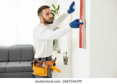 man plasterer construction worker at work, takes plaster from bucket and puts it on trowel to plastering the wall, wears helmet inside the building site of a house