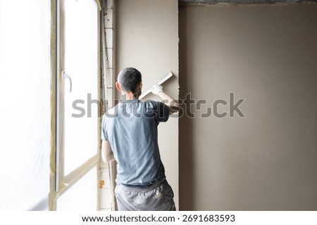man plasterer construction worker at work with trowel, plastering a wall.