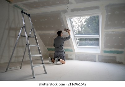Man plastering drywall in a private house. - Shutterstock ID 2116961642