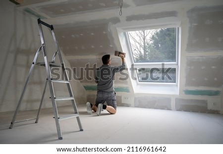 Man plastering drywall in a private house.