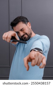 Man playfully poses with smartphone while making a fun gesture in a modern indoor setting