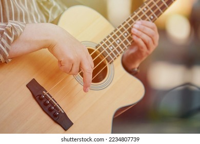 Man playing acoustic bass guitar at outdoor event, close up view to wooden guitar neck. Right handed bass player man playing four strings bass guitar, very nimble fingers of street music artist - Shutterstock ID 2234807739