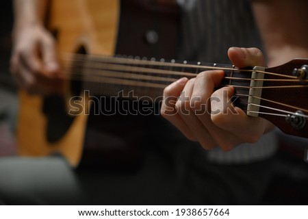 Man playing acoustic guitar, cover for online courses, learning at home.