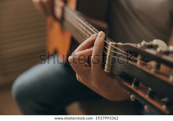 Man playing acoustic guitar, cover for online\
courses, learning at home