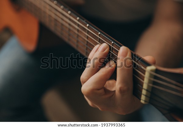 Man playing acoustic guitar, cover for online\
courses, learning at home