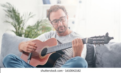 Man Playing Acoustic Guitar In The Living Room.